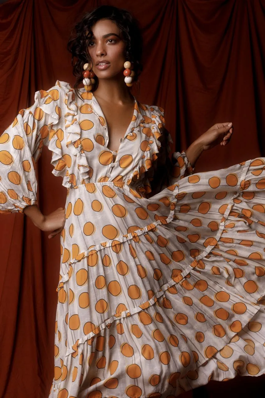 Anaiza Ferreira in a polka dot ruffled dress against a red curtain